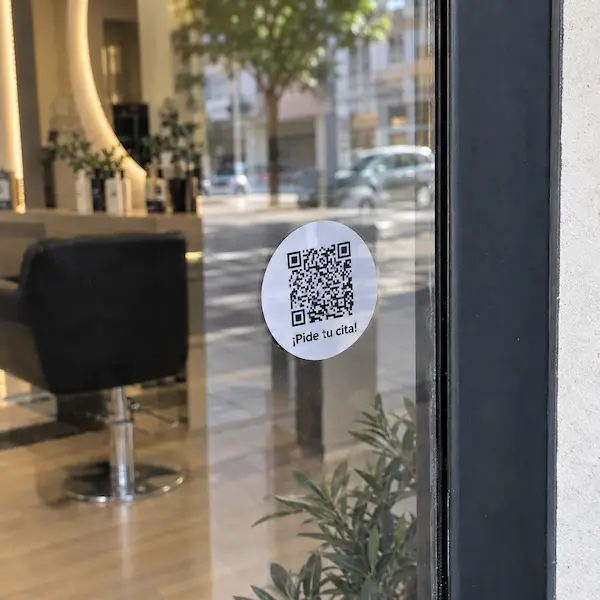 Código QR del enlace de reservas de CitaClic pegado en la puerta de un salón